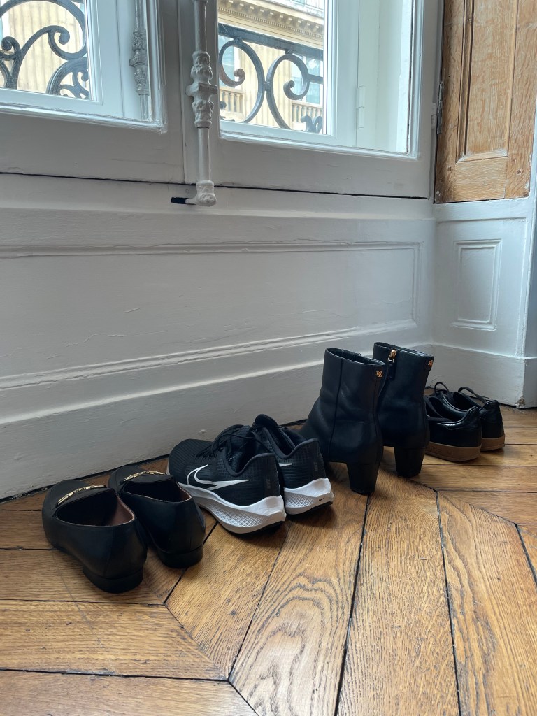 Black shoes neatly put in front of scenic French windows in a classic Paris flat.