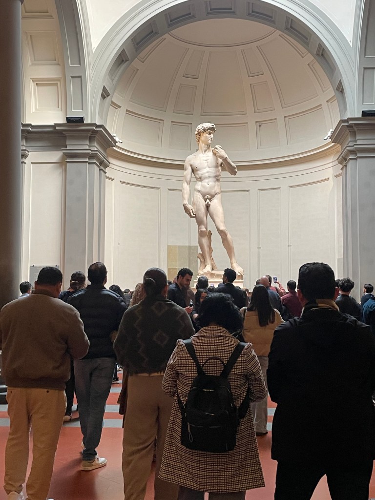 Michelangelo's David in front of a large crowd at the Galleria dell'Academia.