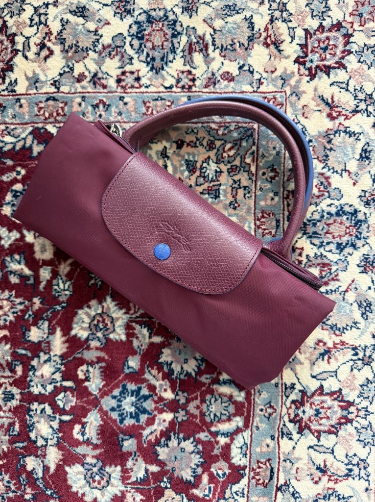 Burgundy Longchamp tote folded on a burgundy carpet